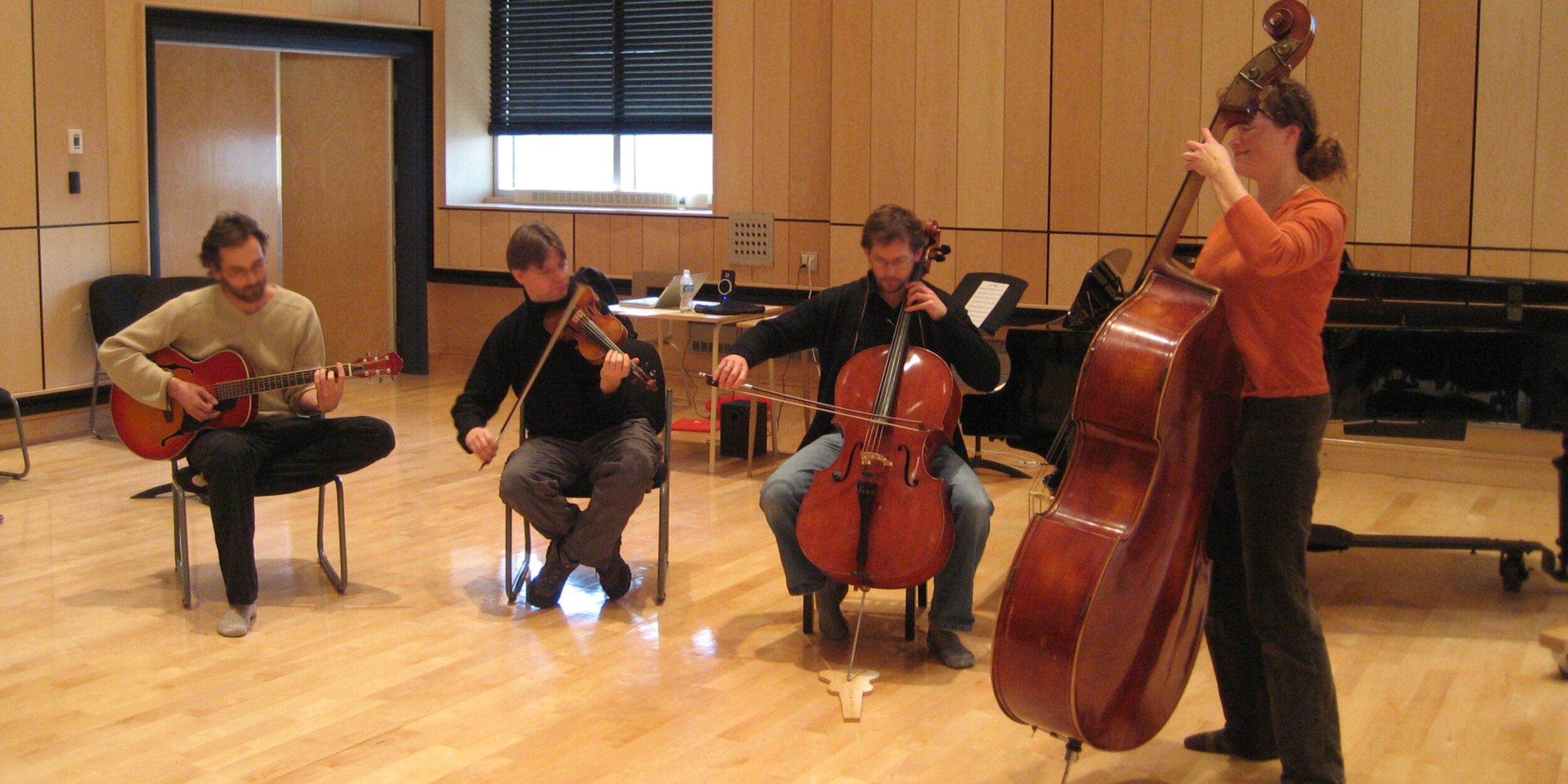 Un ensemble guitare, violon, violoncelle et contrebasse joue en cercle pendant un atelier.